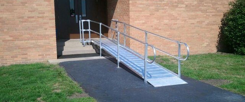 An unappealing metal ramp put on top of part of a small staircase, a perfect example of compliant, but not good.